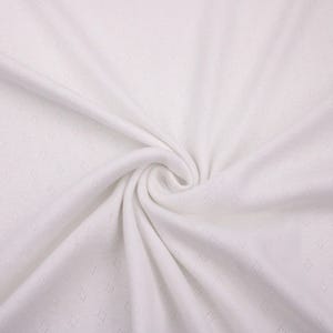 Puede incluir: Tela blanca con un patr&oacute;n texturizado en forma de diamante. La tela es suave y tiene una superficie lisa y uniforme.
