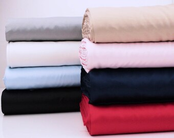 May include: A stack of six fabric rolls in different colors, including gray, white, light blue, navy blue, red, and beige.
