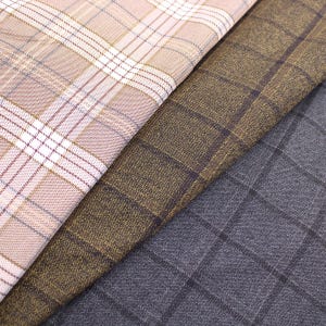 Op de afbeelding: Drie verschillende stoffen met ruitjes, een in lichtbruin en wit, een in donkerbruin en goud en een in donkergrijs en zwart.