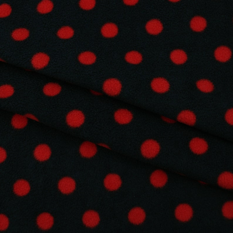 May include: Black fabric with a red polka dot pattern. The fabric is soft and fuzzy, and the dots are evenly spaced.