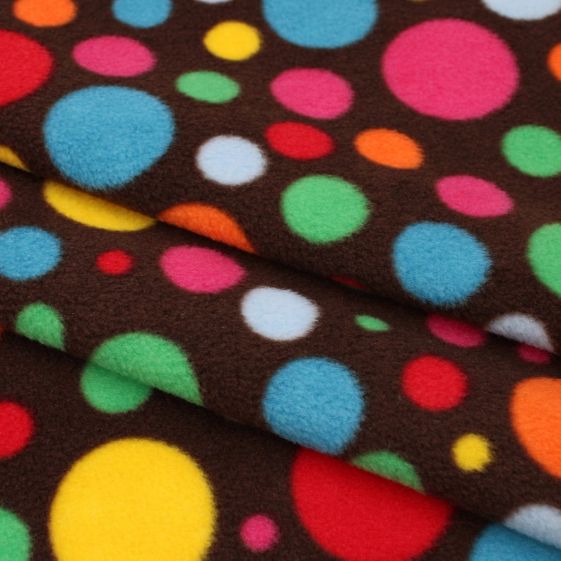 May include: Brown fabric with a repeating pattern of colourful polka dots. The dots are various sizes and colours, including red, blue, green, yellow, and pink.