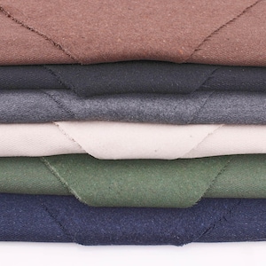 May include: A stack of six fabric swatches in different colors, including brown, gray, beige, green, and blue. The fabric is folded over and the edges are visible.