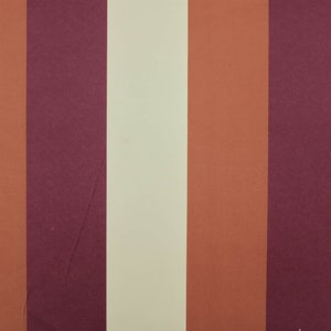 Può includere: Un tessuto a righe con bande alternate di color borgogna, crema, arancio e borgogna.