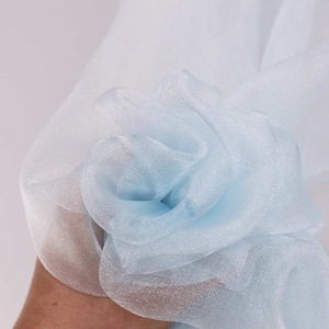Könnte beinhalten: Nahaufnahme eines hellblauen, durchsichtigen Stoffes, der seine zarte Textur und seinen weichen Fall zeigt.
