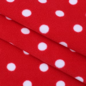 May include: Red fleece fabric with white polka dots. The fabric is folded in thirds, showing the pattern on both sides.
