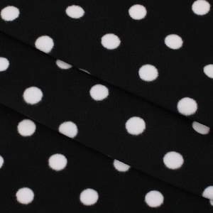 May include: Black fleece fabric with white polka dots. The fabric is folded in thirds, showing the pattern.