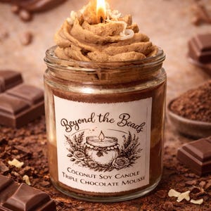 May include: A lit candle in a glass jar with a chocolate mousse topping. The jar has a label that reads "Beyond the Beads Coconut Soy Candle Triple Chocolate Mousse". Chocolate bars and cocoa powder surround the jar.