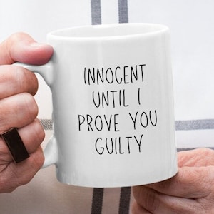 May include: White ceramic mug with black text that reads "Innocent until I prove you guilty".