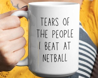 May include: White ceramic coffee mug with black text that reads "Tears of the people I beat at netball".