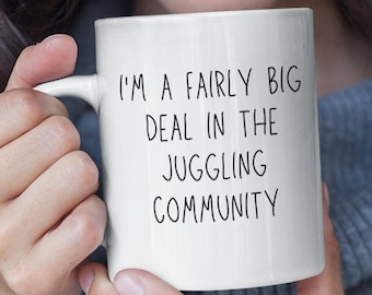 May include: White ceramic mug with black text that reads "I'm a fairly big deal in the juggling community."