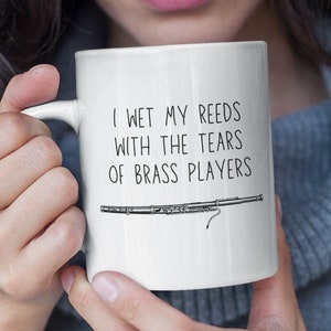 May include: White ceramic mug with a black illustration of a clarinet and the text "I wet my reeds with the tears of brass players".