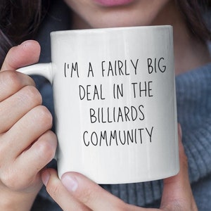 May include: White ceramic coffee mug with black text that reads "I'm a fairly big deal in the billiards community."