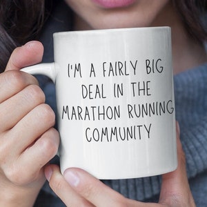 May include: White ceramic mug with black text that reads "I'm a fairly big deal in the marathon running community".