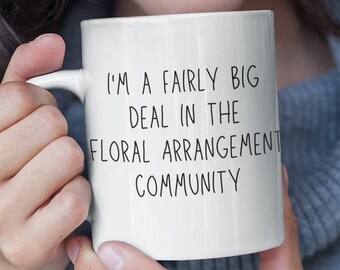 May include: A white ceramic mug with a black inscription that reads "I'm a fairly big deal in the floral arrangement community".