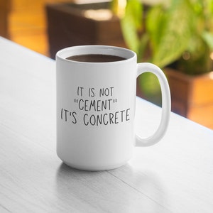 May include: White ceramic coffee mug with a black handwritten message that reads "It is not "cement" it's concrete".