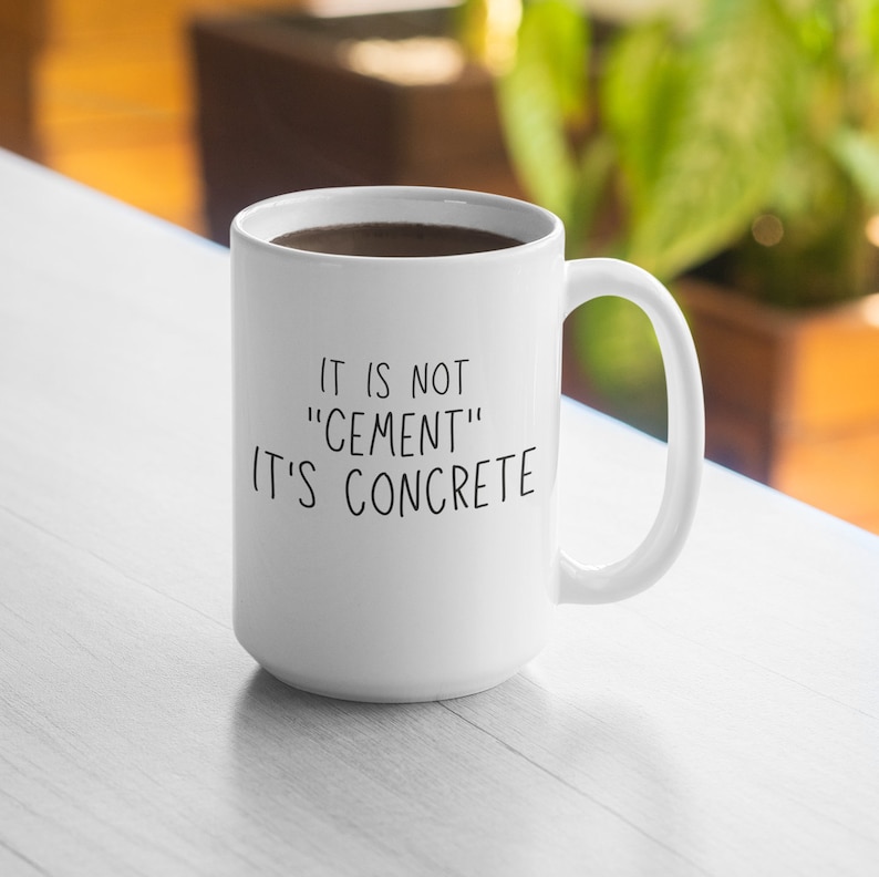 May include: White ceramic coffee mug with a black handwritten message that reads "It is not "cement" it's concrete".