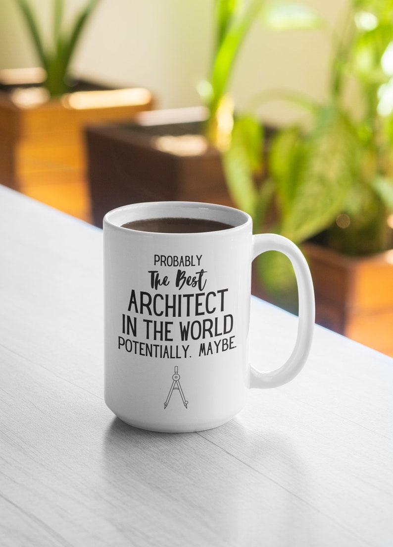 May include: White ceramic coffee mug with black text that reads "Probably the best architect in the world potentially. Maybe." and a compass symbol at the bottom.