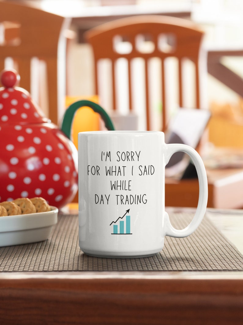 May include: White ceramic coffee mug with black text that reads "I'm sorry for what I said while day trading" with a blue upward trending graph.