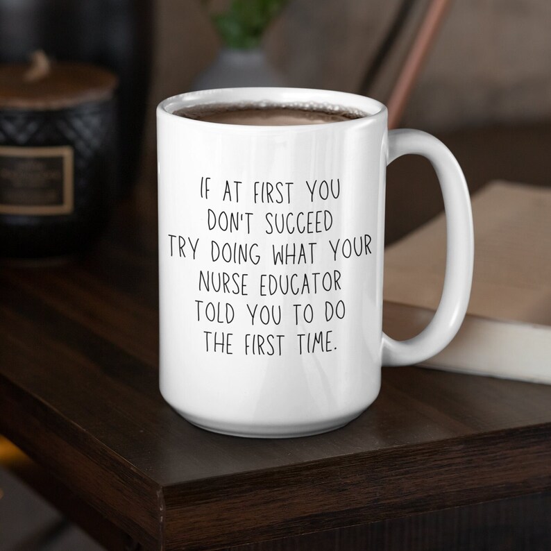 Puede incluir: Taza de caf&eacute; de cer&aacute;mica blanca con asa negra. La taza tiene una cita humor&iacute;stica impresa: "Si al principio no tienes &eacute;xito, intenta hacer lo que tu educador de enfermer&iacute;a te dijo que hicieras la primera vez."