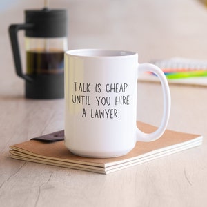 May include: White coffee mug with black text that reads "Talk is cheap until you hire a lawyer."
