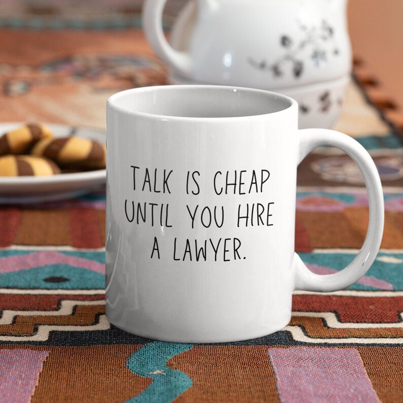 May include: White ceramic coffee mug with black text that reads "Talk is cheap until you hire a lawyer."