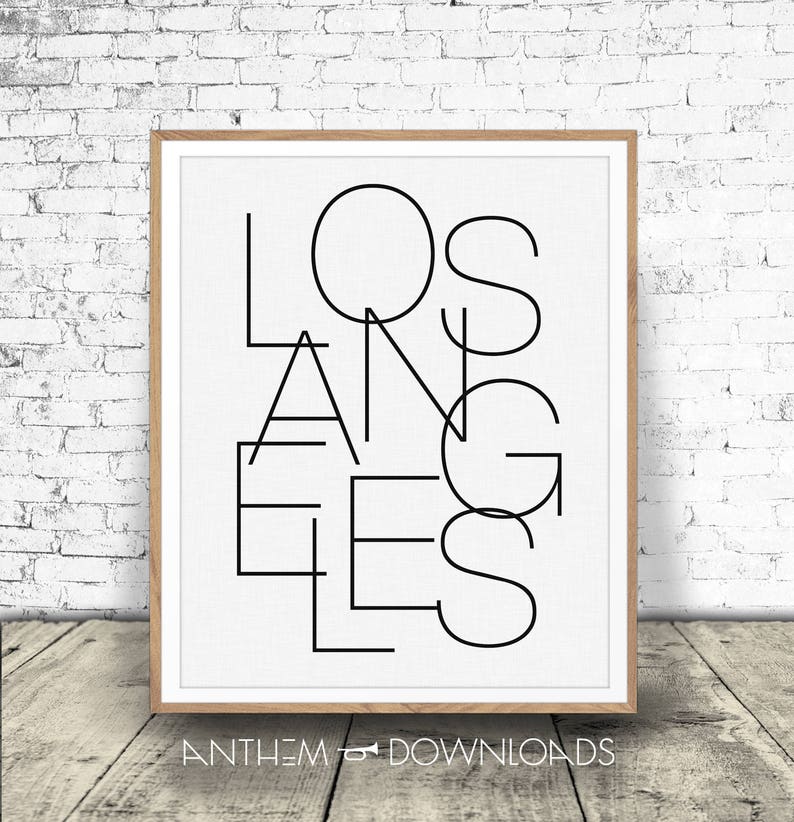May include: Black and white graphic print of the word "Los Angeles" in a modern, geometric style. The print is framed in a light wood frame.