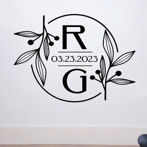Może przedstawiać: Czarno-biały monogram z literami "R" i "G" w kółku z kwiatowym wzorem. Data "03.23.2023" jest napisana pod literami.