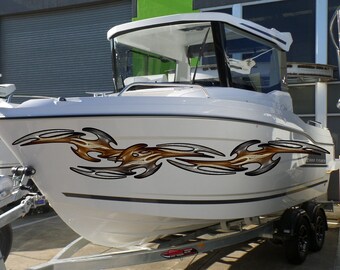 Könnte beinhalten: Weißes Boot mit einem braunen und silbernen Tribal-Flammen-Aufkleber an der Seite. Das Boot steht auf einem Anhänger mit schwarzen Rädern.