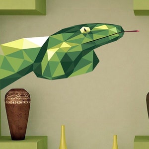 May include: A geometric green snake wall art piece with a red tongue extends from a recessed wall. The wall features decorative vases in brown and yellow, and three black square frames. The wall is painted in a light green color.