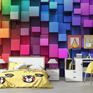 May include: A bedroom with a colorful 3D cube patterned wall mural. The room features a bed with a yellow duvet cover with black bear illustrations and the words "I love you". There is a white desk with a yellow chair and a white nightstand with a lamp.
