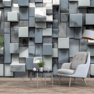 May include: A modern living room with a gray and white geometric wall design. The room features a light gray armchair, a small black side table, and a floor lamp. Potted plants add a touch of nature to the space.