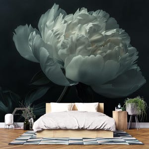Può includere: Un grande e dettagliato fiore di peonia bianca su sfondo scuro. I petali sono strutturati e stratificati, creando un senso di profondità. L'immagine è un murale di carta da parati, con un letto e altri mobili da camera da letto in primo piano.
