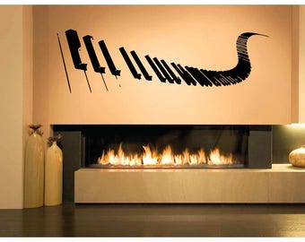 May include: A black piano keys wall decal in a flowing design. The decal is applied to a beige wall above a fireplace with a glowing fire. Decorative vases are on the left.