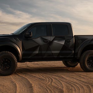May include: Black Ford Raptor pickup truck with geometric pattern on the side panels. The truck has large off-road tires and is parked on a sandy surface. The background features a desert landscape and a cloudy sky.