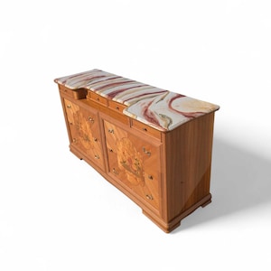 May include: A wooden cabinet with a marble top. The marble top features a pattern of red, white, and tan swirls. The cabinet doors have decorative panels with a floral design. The cabinet has brass hardware and a curved front.