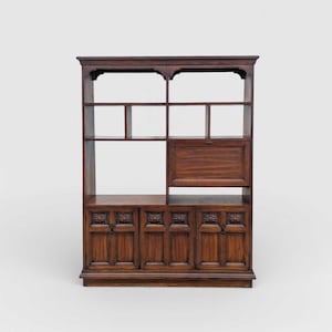 May include: A dark brown wooden bookcase with multiple shelves and cabinets. The upper section has open shelves, while the lower section features cabinet doors with carved floral designs. A small cabinet with a drop-down door is in the middle.