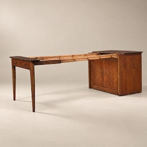 May include: A brown wooden extendable table featuring a solid cabinet base with two doors on one side and a single leg support on the other. The table surface is partially extended, revealing a series of wooden slats that connect the two main sections.