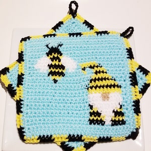 May include: A pair of crocheted pot holders with a bee and a gnome design. The pot holders are blue, yellow, black, and white.