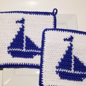 May include: Two white crocheted pot holders with blue sailboat designs.