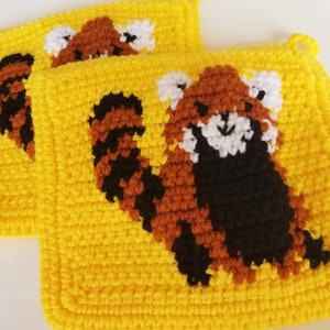 May include: Two yellow crocheted pot holders with red panda designs. The red pandas are crocheted in brown, black, and white yarn.