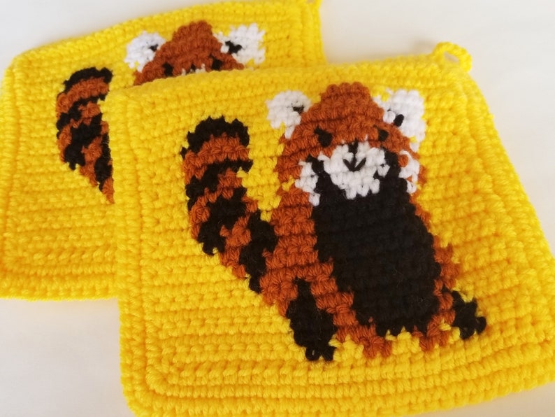 May include: Two yellow crocheted pot holders with red panda designs. The red pandas are crocheted in brown, black, and white yarn.