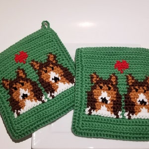 May include: Two green crocheted pot holders with a red heart and two brown and white dogs on each.