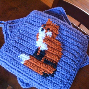 May include: A purple crocheted pillow with a fox design in orange, white, and black.