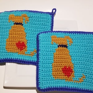 May include: Two crocheted pot holders with a blue background and a brown dog with a red heart on it.