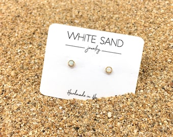 May include: A pair of small, white opal stud earrings on a white card with the text "WHITE SAND jewelry" and "Handmade in Hawaii".