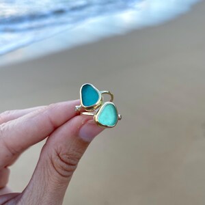 May include: A gold ring featuring two pieces of sea glass, one turquoise and one light blue.