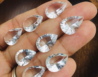 Puede incluir: Ocho colgantes de lágrima de cristal de cuarzo transparente, cada uno con un diseño facetado, se muestran en una mano.
