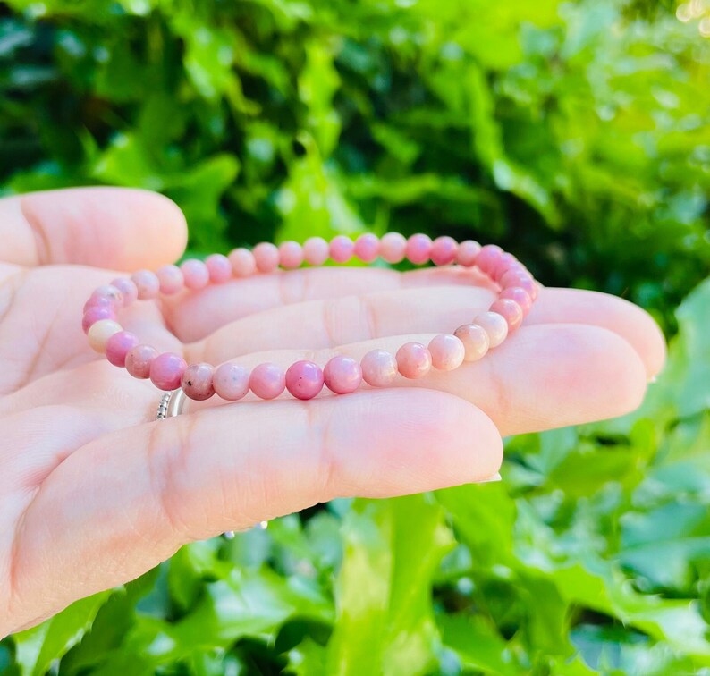 K&ouml;nnte beinhalten: Ein rosafarbenes Edelstein-Armband mit kleinen runden Perlen. Das Armband besteht aus nat&uuml;rlichen Steinen und ist ein wundersch&ouml;nes Accessoire f&uuml;r jeden Anlass.