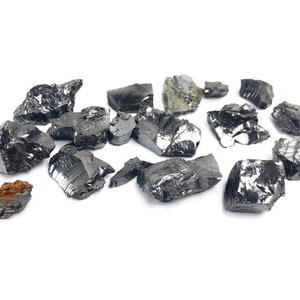 May include: A collection of black, shiny, irregularly shaped, rough-edged, natural mineral stones on a white background.