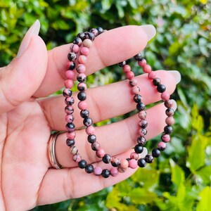 May include: Two pink and black gemstone bracelets with small round beads.